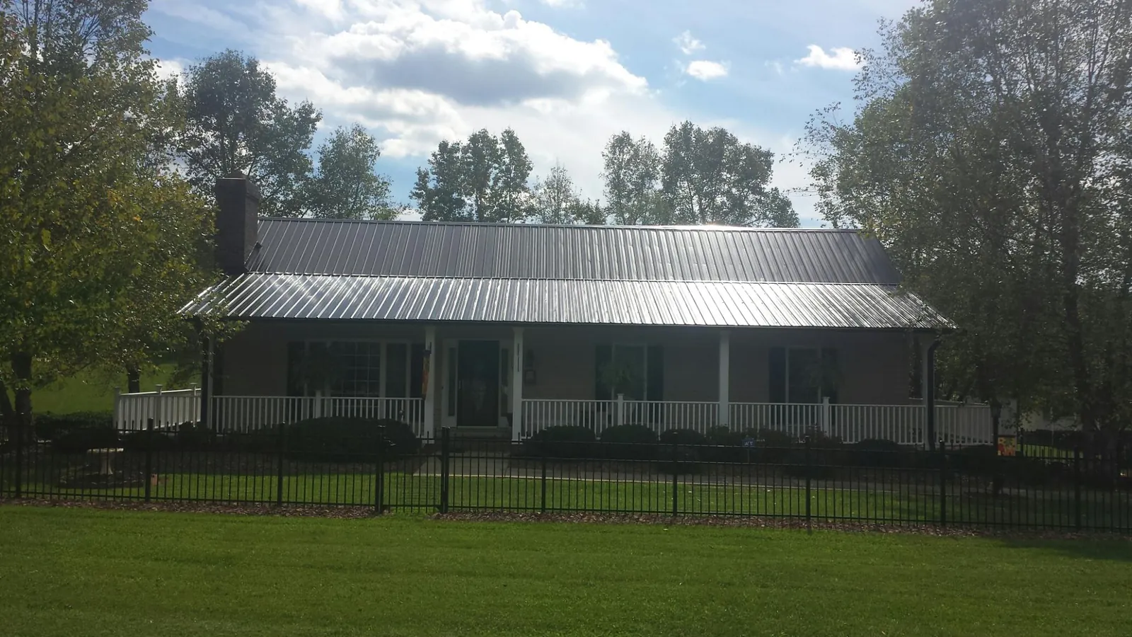 Gray metal roof on a brick ranch with a full width front porch — Gutter Guard Installation work by our crew in Ames