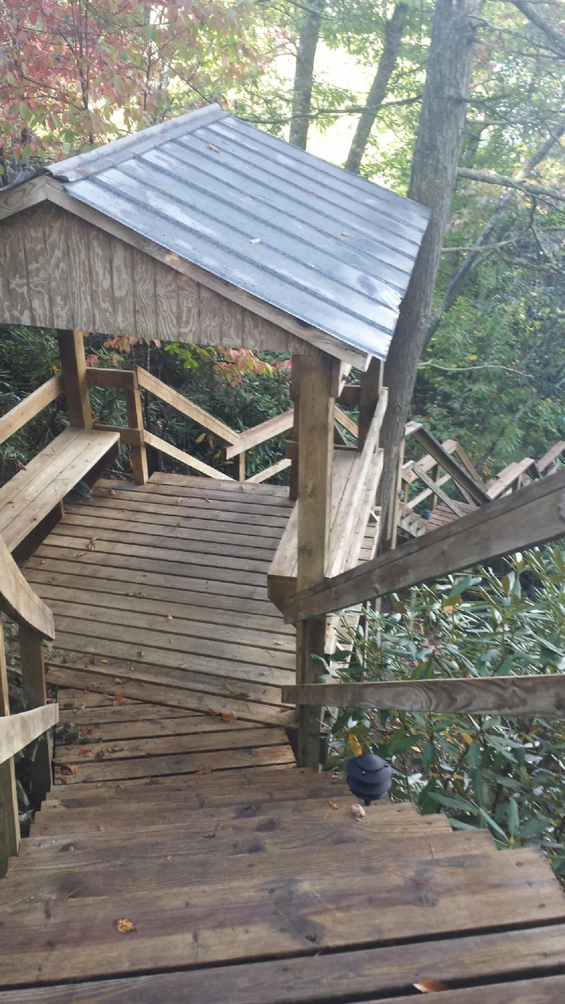 Metal roofed shelter over wooden steps on a wooded walkway — Skylight Repair & Installation work by our crew in Ames