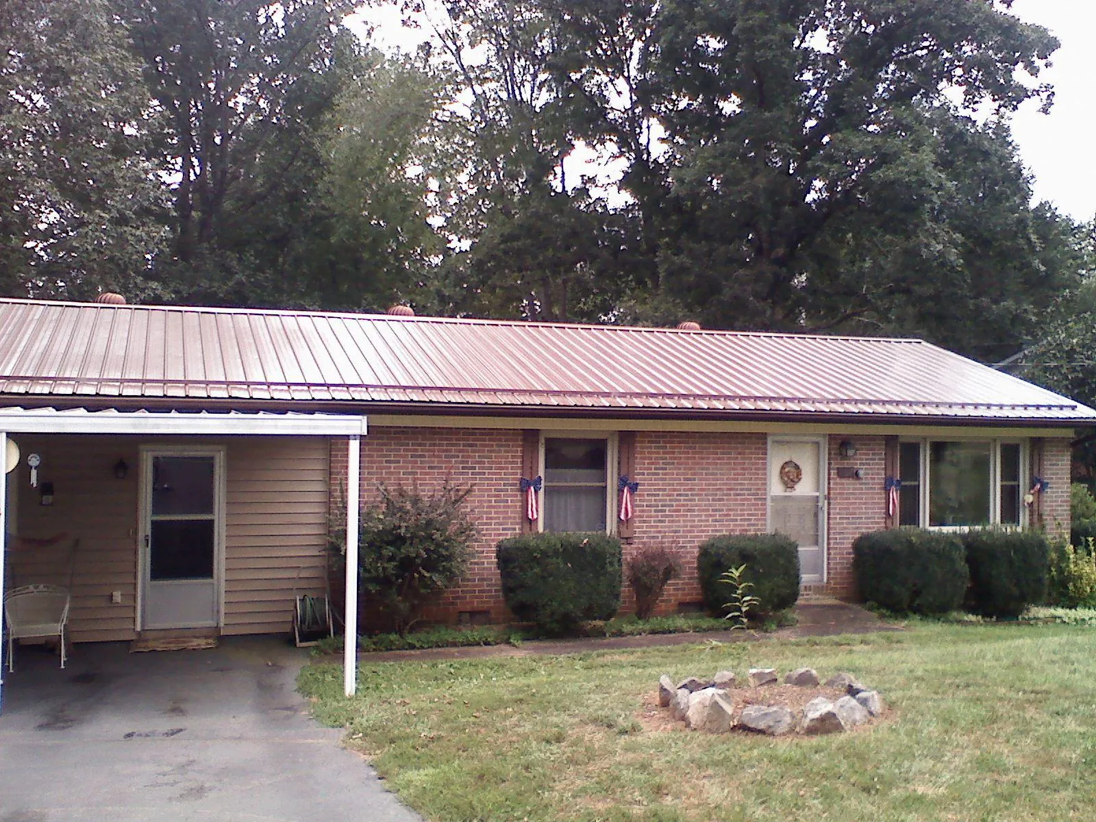 Bronze metal roof and carport on a brick ranch home — Roof Repair work by our crew in Ames
